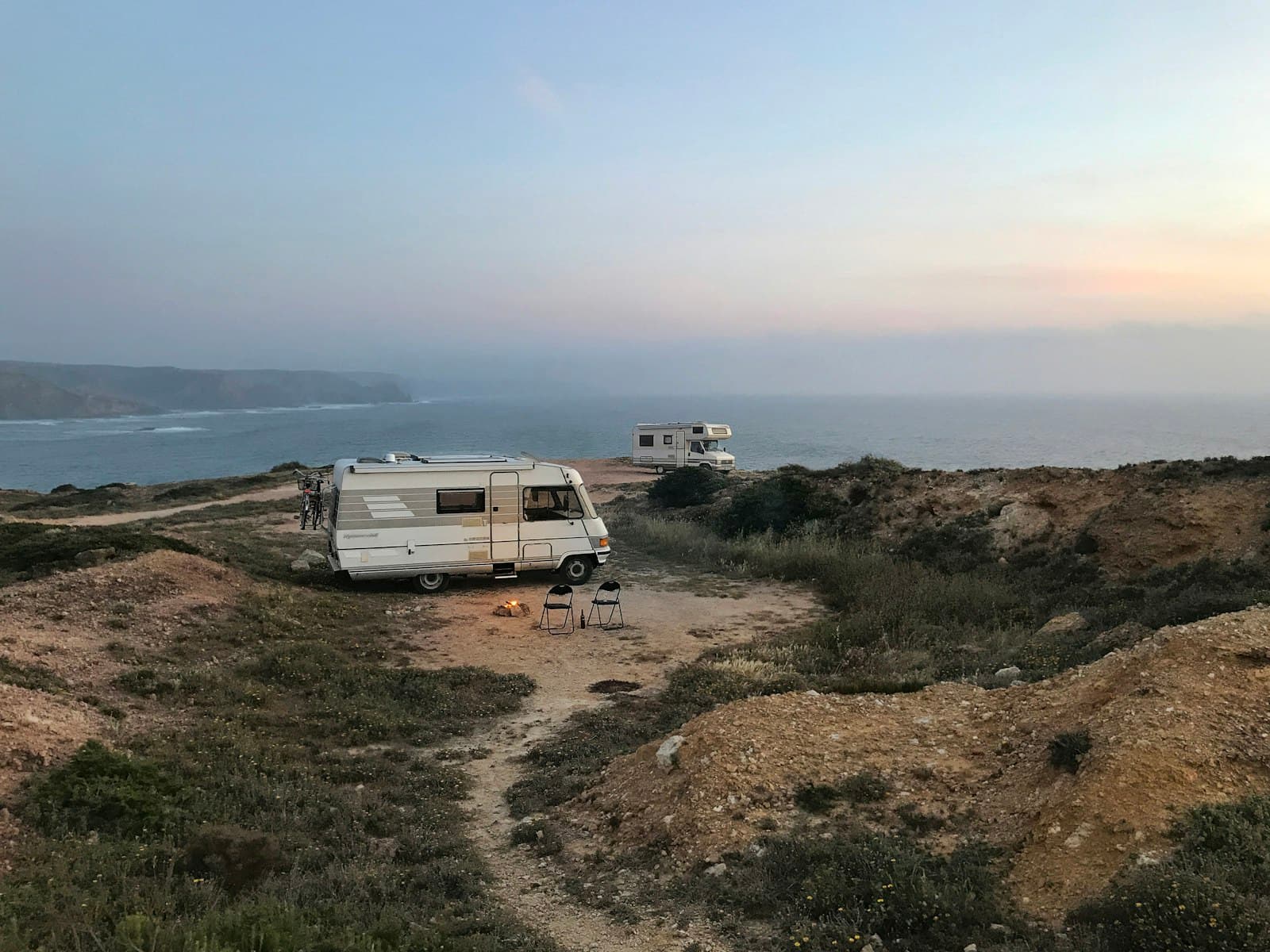 Camping-cars en bivouac sur une falaise au bord de la mer au coucher du soleil